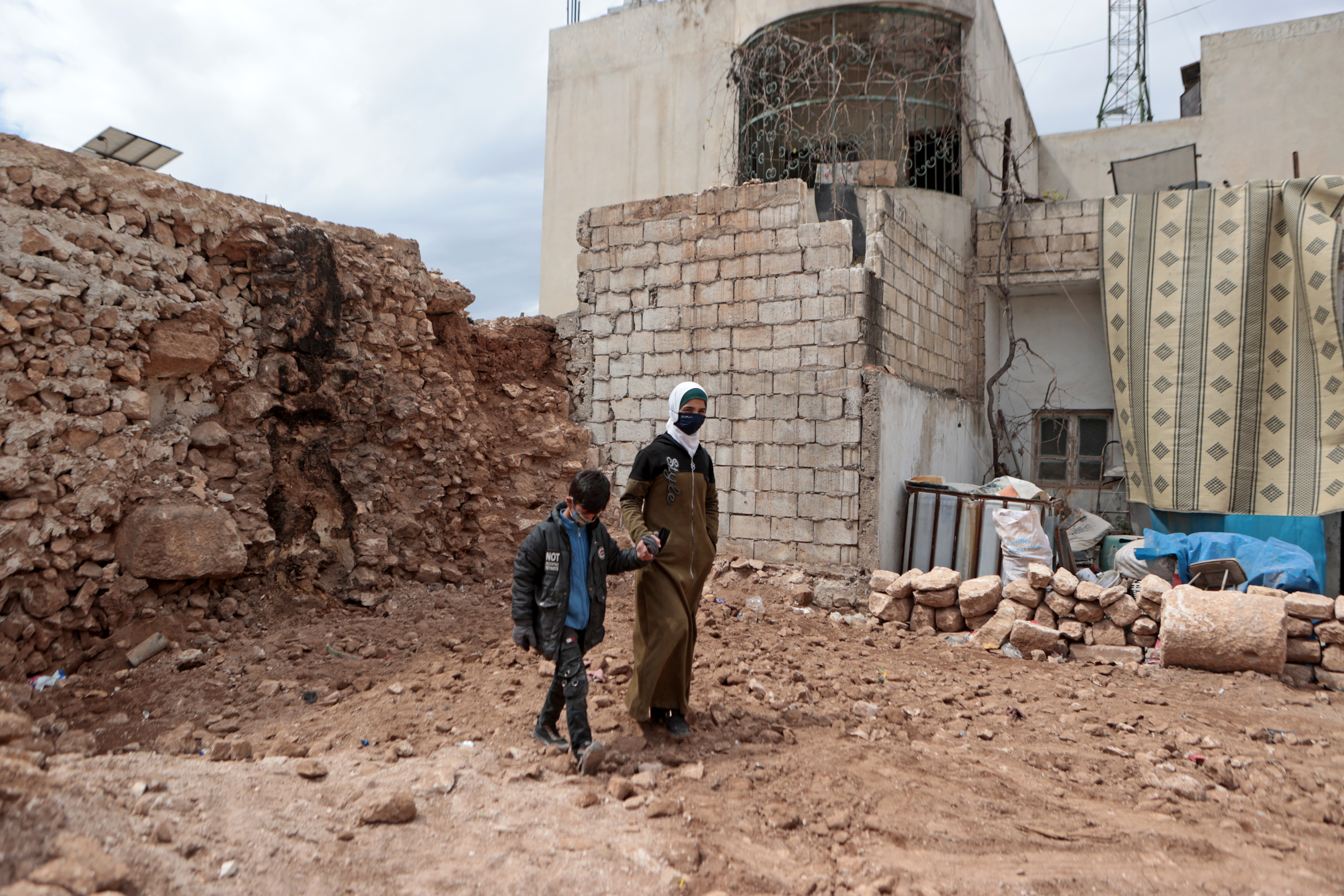 Une femme et un enfant marchent à travers des ruines