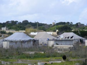 Des habitations derrière un grillage et des éléments de construction en béton