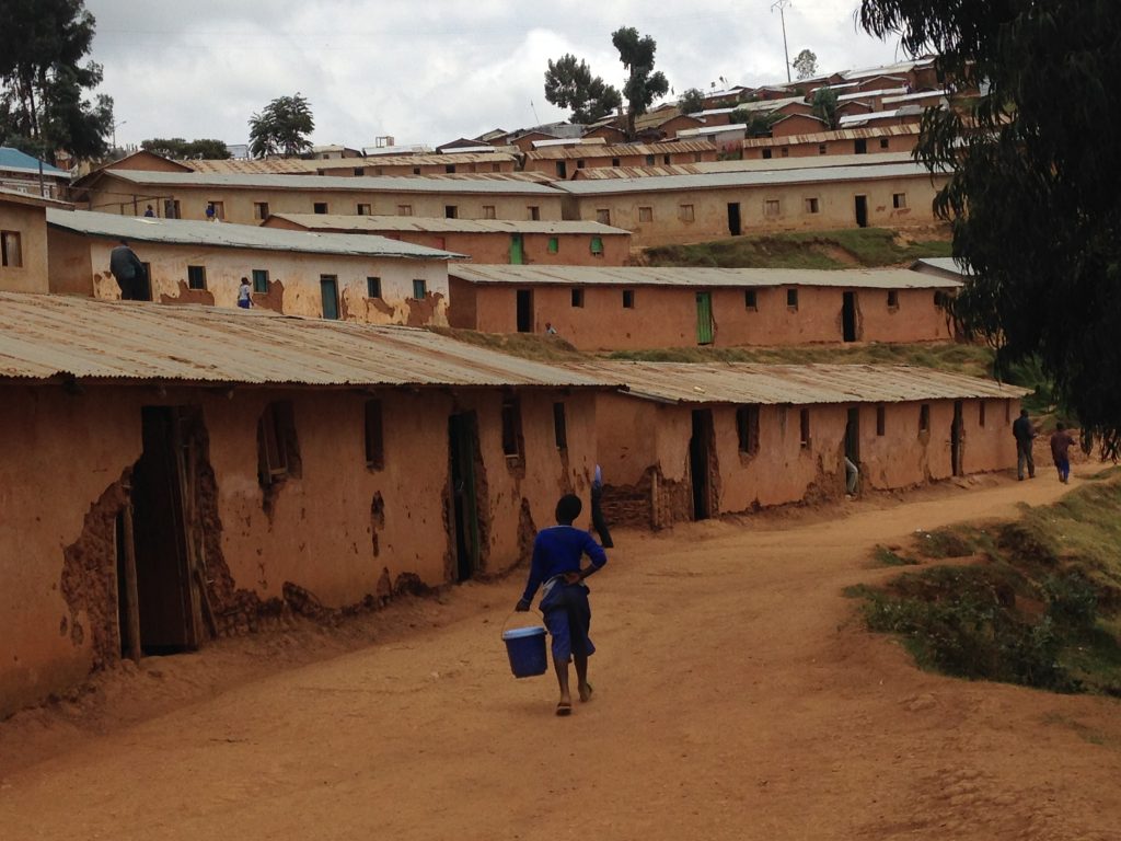Un garçon avec un seau devant des maisons